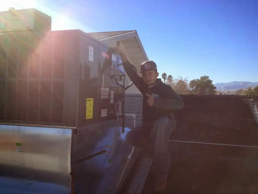 HVAC technician performing Air Duct Cleaning on a rooftop unit in Groton