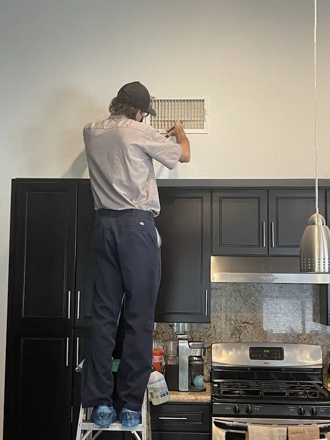 Technician inspecting an air vent during HVAC service in Groton